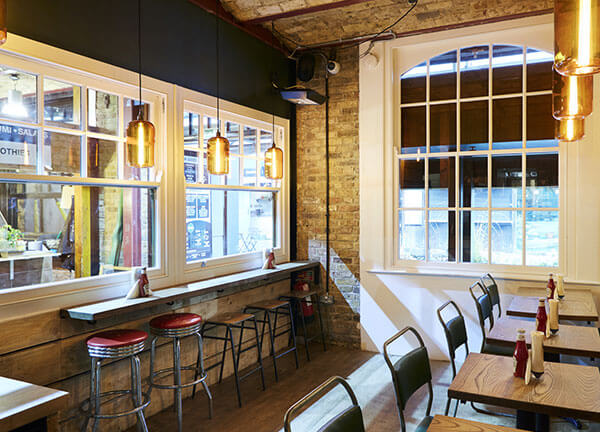 Bench seating with hanging lights and lots of natural light inside the Camden restaurant