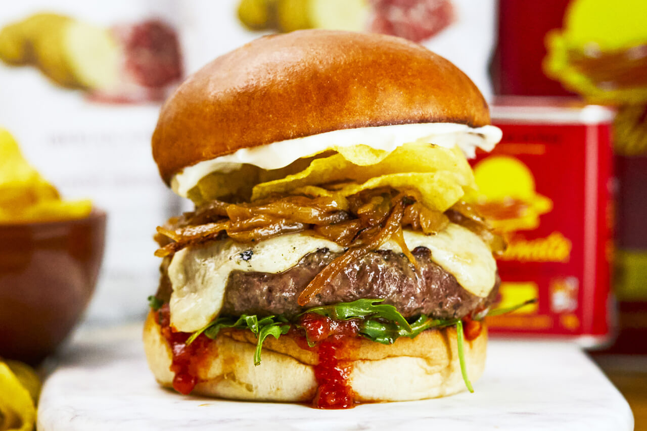 Barcelona - A beef burger, Torres Jamon Iberico crisps, manchego cheese, grilled onions, bravas sauce, rocket, confit garlic mayo, with rosemary chips