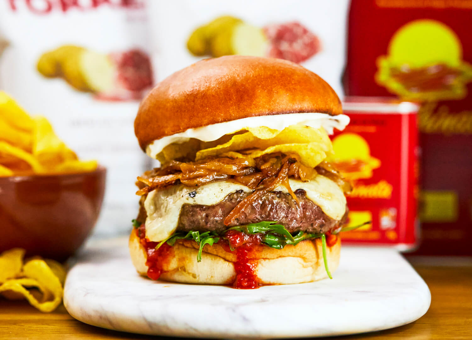 Barcelona - A beef burger, Torres Jamon Iberico crisps, manchego cheese, grilled onions, bravas sauce, rocket, confit garlic mayo, with rosemary chips